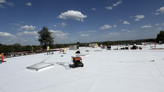 Crew installing TPO single-ply on a large commercial roof