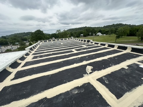 Roof mid-job with every seam sealed in white before the field coat